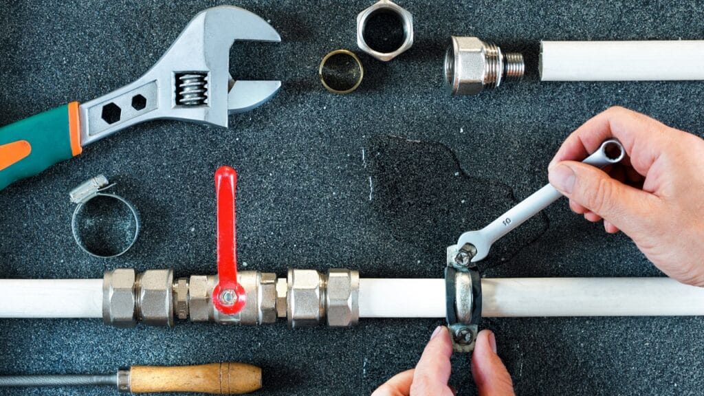 Plumber repairing a pipe valve with an adjustable wrench in Spring Valley