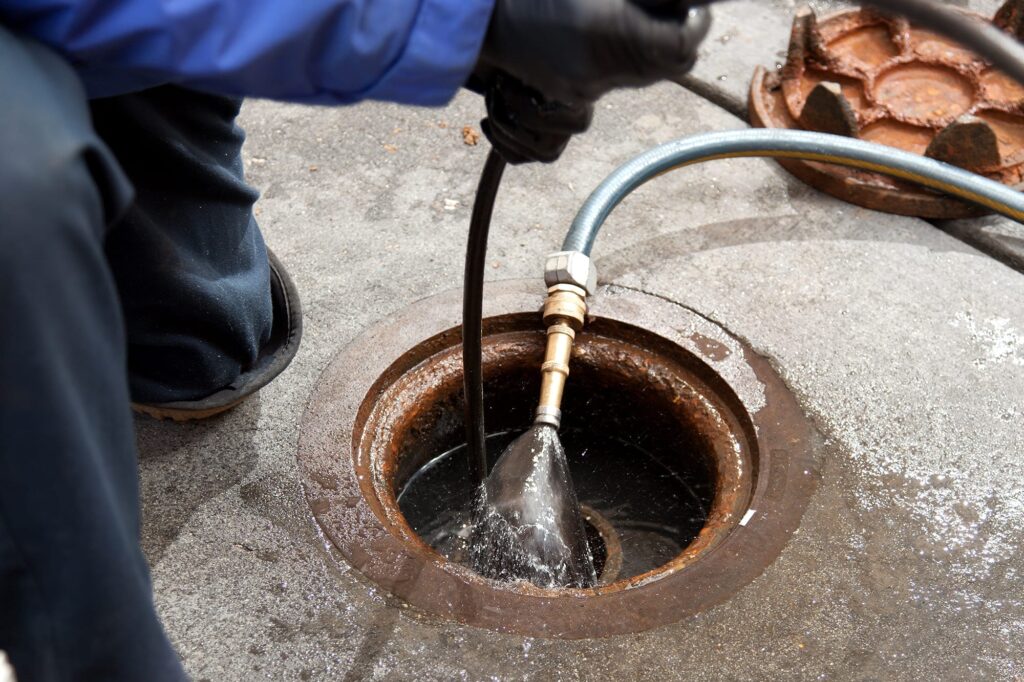 Plumber hydro jetting a sewer line through a manhole in Spring Valley