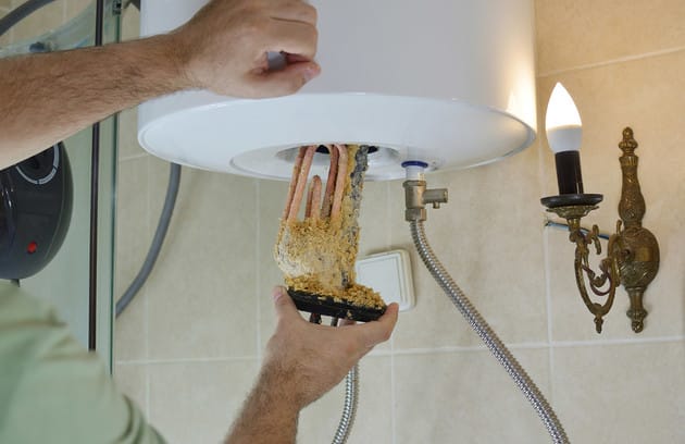 Technician removing mineral buildup from a water heater in Spring Valley
