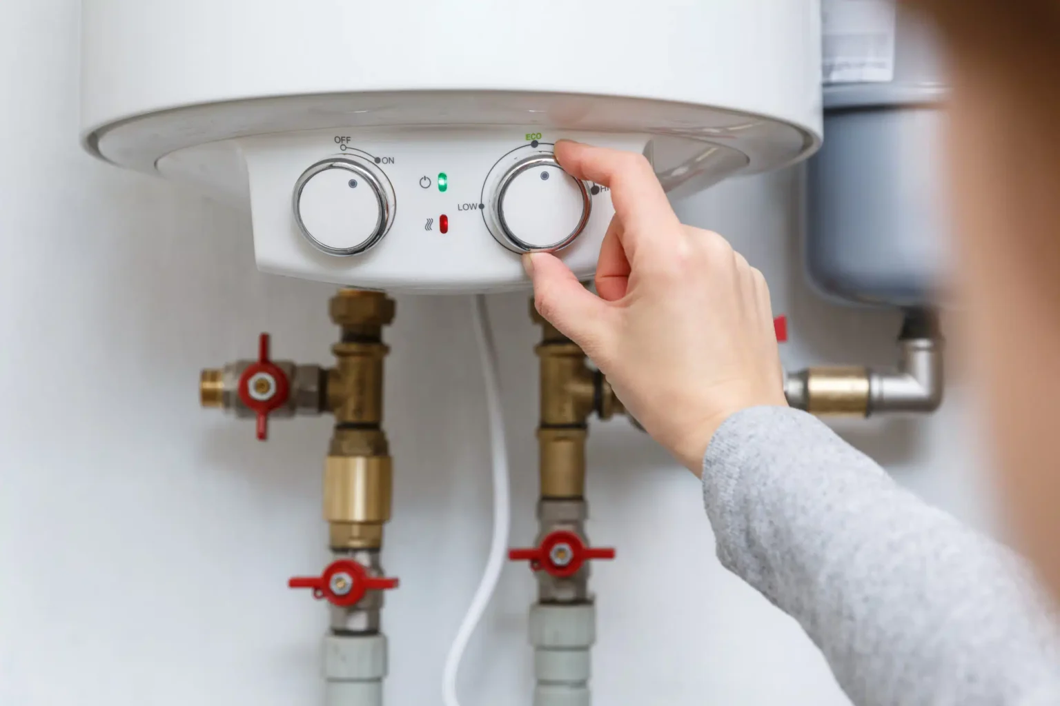 Homeowner adjusting the temperature controls on a water heater in Spring Valley
